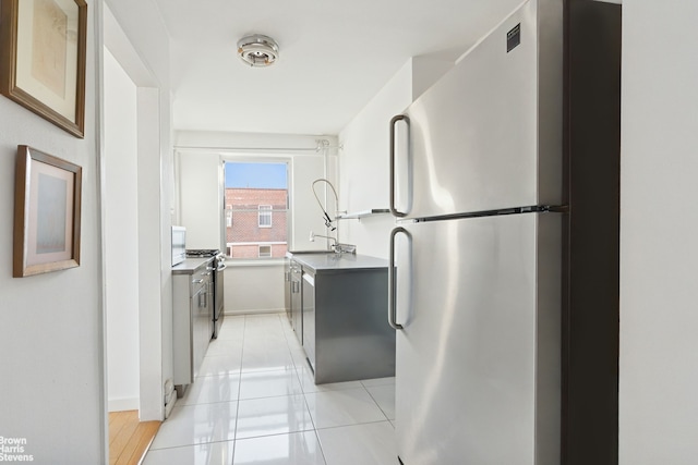 kitchen with stainless steel appliances, baseboards, light tile patterned floors, and a sink