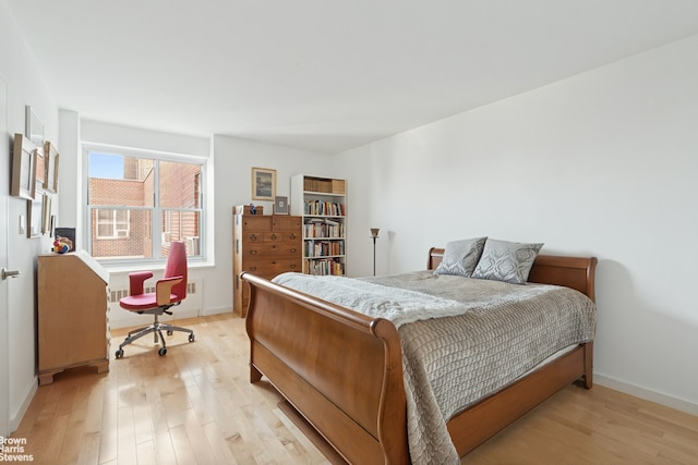 bedroom featuring light wood finished floors, baseboards, and a desk