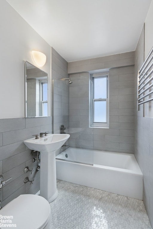 bathroom featuring tile patterned flooring, tiled shower / bath, plenty of natural light, and toilet