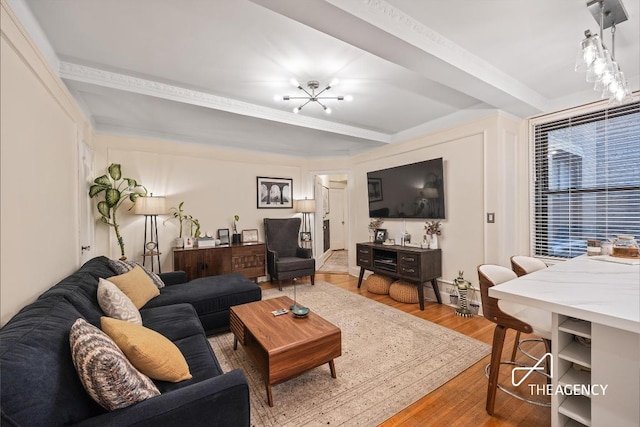 living room with beamed ceiling, crown molding, a notable chandelier, and light hardwood / wood-style floors