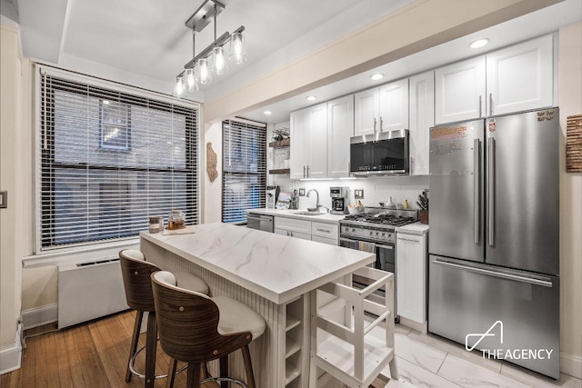 kitchen featuring a sink, white cabinetry, hanging light fixtures, appliances with stainless steel finishes, and open shelves