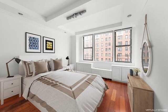 bedroom with dark hardwood / wood-style floors and a raised ceiling