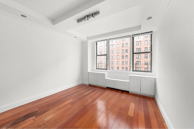 empty room with hardwood / wood-style floors and a tray ceiling