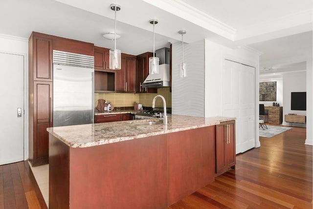 kitchen with wall chimney exhaust hood, sink, dark hardwood / wood-style floors, pendant lighting, and light stone countertops