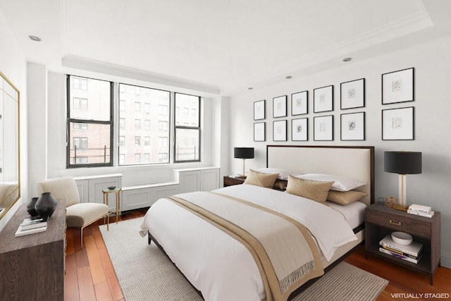 bedroom with a raised ceiling, crown molding, and dark hardwood / wood-style flooring