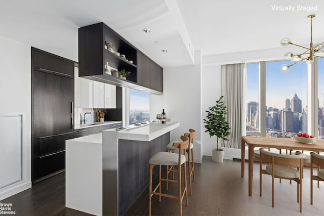 kitchen with sink, a breakfast bar area, a chandelier, kitchen peninsula, and dark wood-type flooring