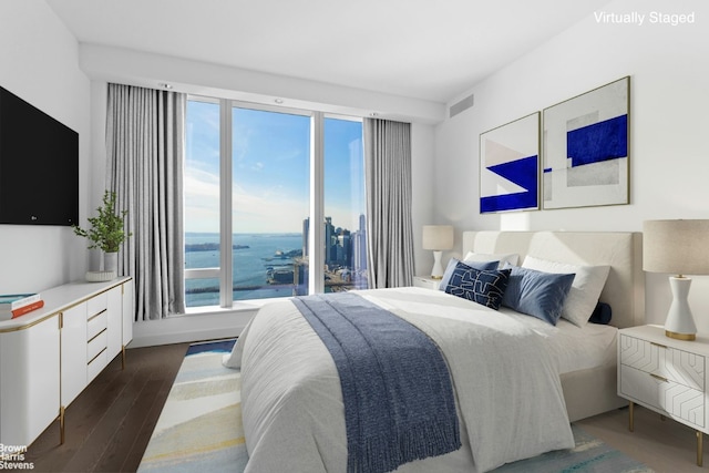 bedroom with a water view and dark hardwood / wood-style flooring