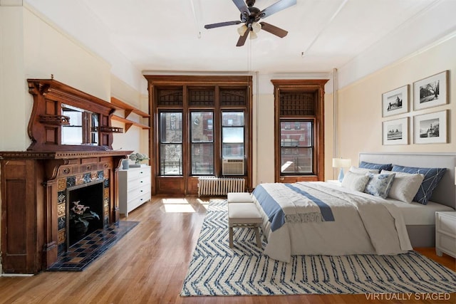 bedroom with hardwood / wood-style flooring, a high end fireplace, and radiator