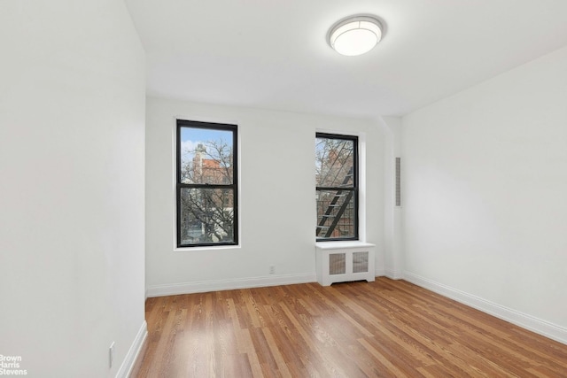 spare room with a healthy amount of sunlight, radiator, and light hardwood / wood-style floors