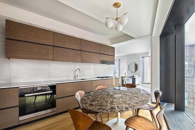 kitchen featuring stainless steel gas stovetop, oven, decorative backsplash, dark brown cabinetry, and light hardwood / wood-style floors