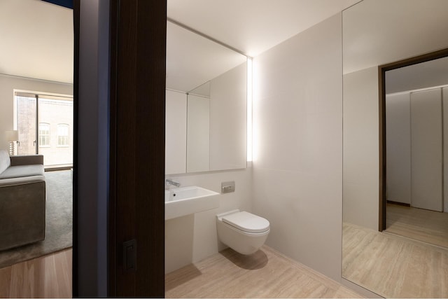551 W 21st St Unit 4F, New York City, NY 10011 - half bathroom featuring toilet, a sink, and wood finished floors