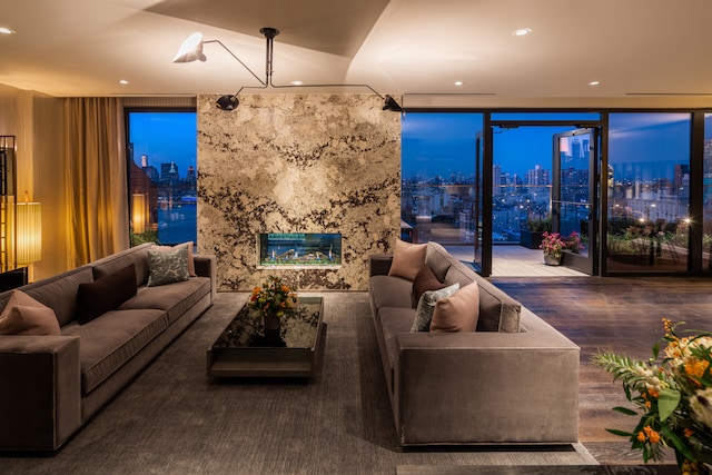 living room featuring a premium fireplace, a wall of windows, wood finished floors, and recessed lighting