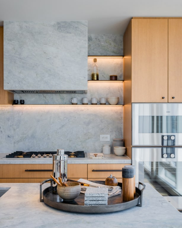 details featuring white gas cooktop, light brown cabinets, stainless steel double oven, and decorative backsplash