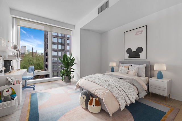 bedroom with visible vents, baseboards, and wood finished floors