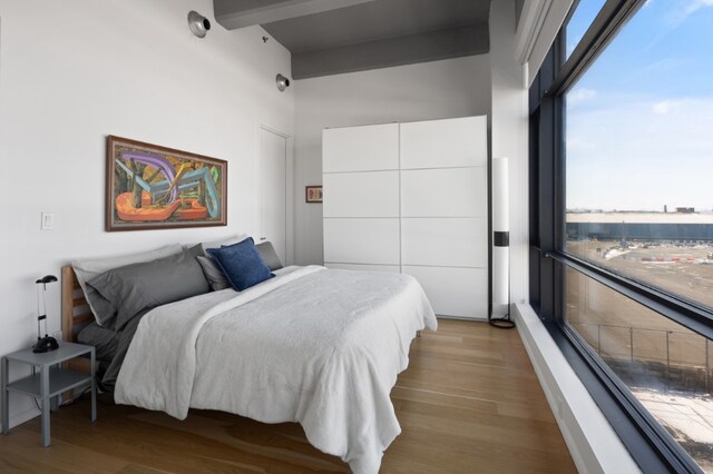 bedroom with beam ceiling and light hardwood / wood-style floors