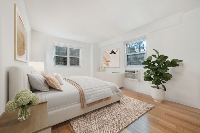 bedroom with cooling unit, radiator heating unit, ornamental molding, and light wood-type flooring