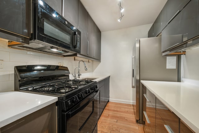 kitchen with sink, light hardwood / wood-style flooring, rail lighting, tasteful backsplash, and black appliances