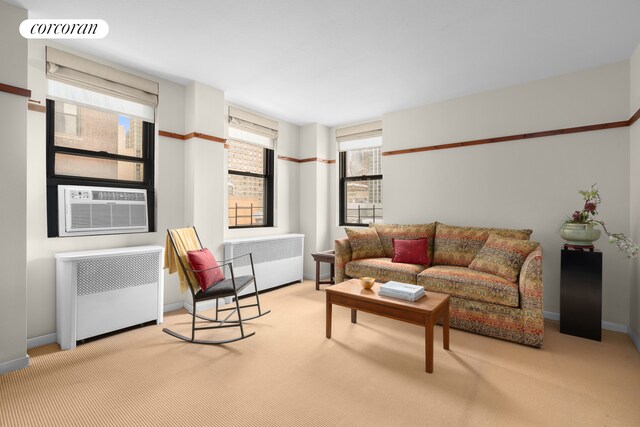 living area featuring light colored carpet, radiator, visible vents, and baseboards