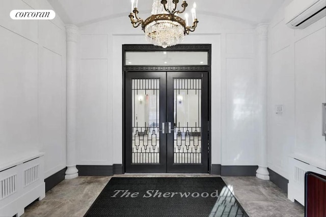 entrance foyer with lofted ceiling, radiator, a wall mounted AC, a notable chandelier, and french doors