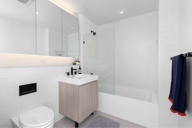 full bathroom with shower / bath combination, toilet, tile patterned floors, vanity, and tile walls