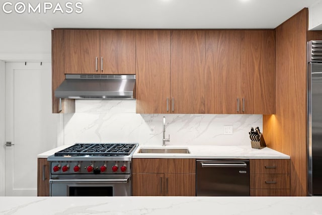 kitchen featuring stainless steel appliances, light stone countertops, sink, and backsplash