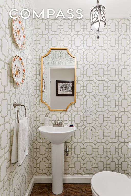 bathroom featuring hardwood / wood-style floors, ornamental molding, and toilet