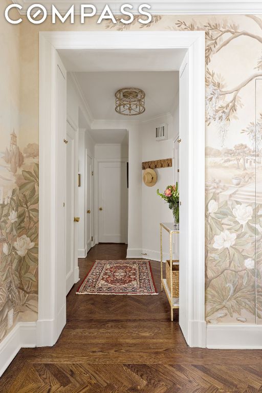 hallway with dark parquet flooring and crown molding