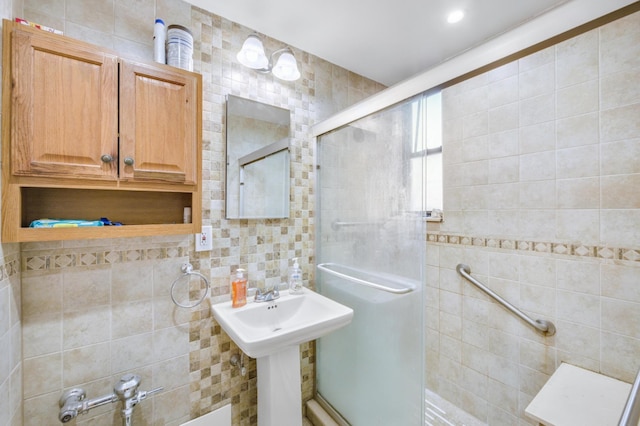 bathroom featuring walk in shower, sink, and tile walls