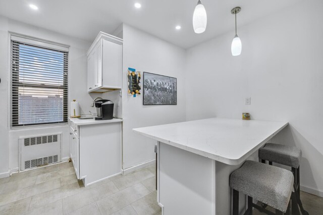 kitchen with a breakfast bar area, light wood-type flooring, appliances with stainless steel finishes, pendant lighting, and white cabinets