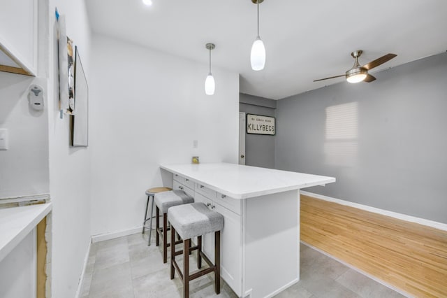 kitchen featuring a breakfast bar, kitchen peninsula, white cabinets, and decorative light fixtures