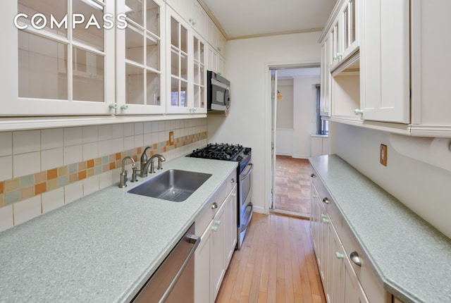 345 E 52nd St Unit 8G, New York City, NY 10022 - kitchen featuring appliances with stainless steel finishes, backsplash, white cabinets, light countertops, and glass insert cabinets