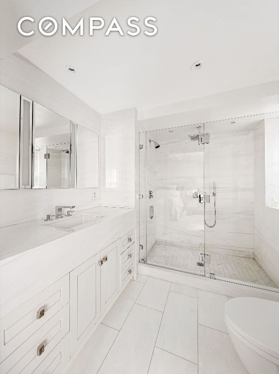 bathroom featuring walk in shower, tile patterned floors, vanity, and toilet