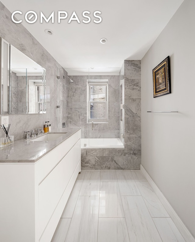 full bathroom with vanity, tile walls, baseboards, and a combined bath / shower with marble appearance