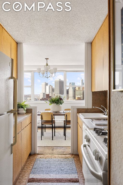 kitchen with pendant lighting, sink, white appliances, and a wealth of natural light