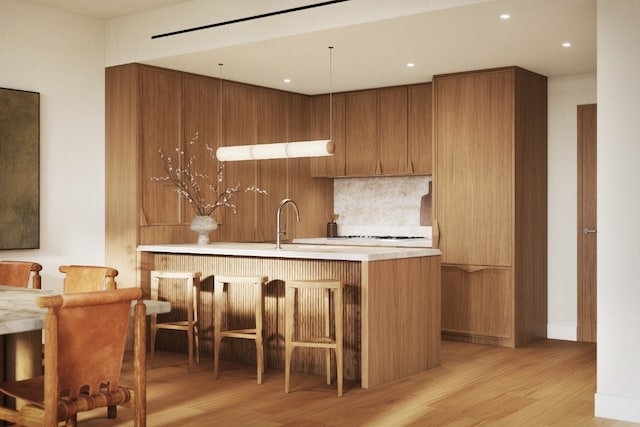 kitchen featuring backsplash, a kitchen breakfast bar, sink, and light wood-type flooring