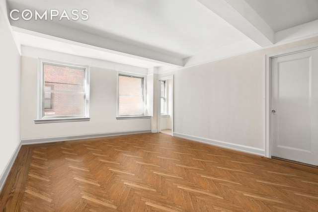 empty room featuring beam ceiling and baseboards