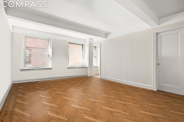 empty room with parquet floors and beamed ceiling