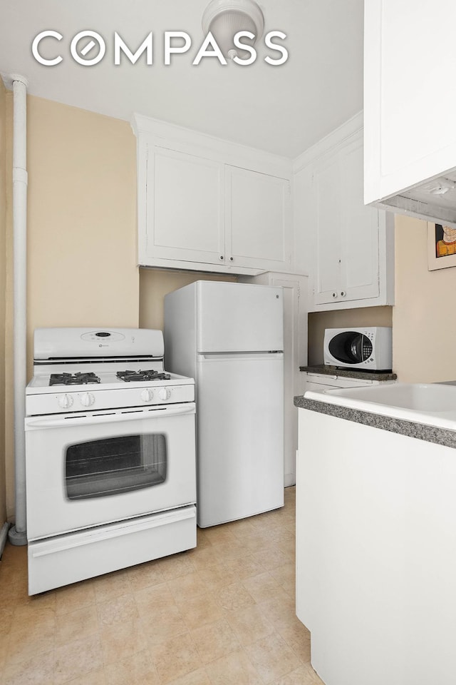 kitchen featuring white appliances, white cabinets, and light countertops