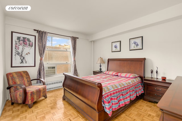 bedroom featuring cooling unit, radiator heating unit, and light parquet flooring