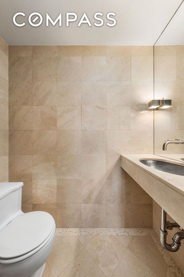 bathroom featuring sink, tile walls, and toilet