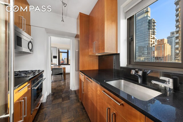 kitchen featuring dark stone countertops, sink, and appliances with stainless steel finishes