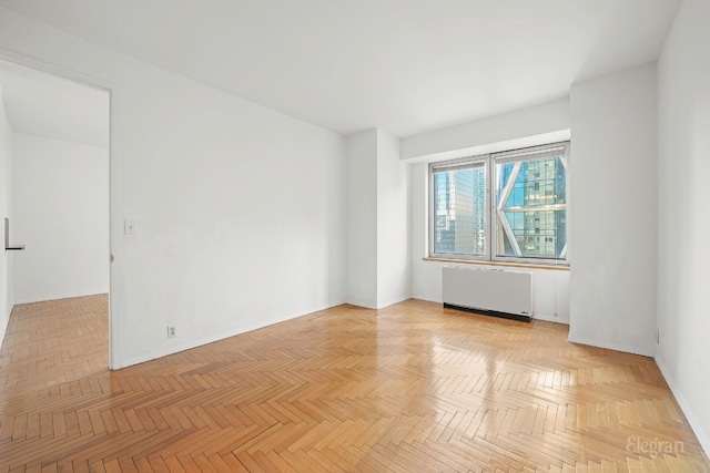 unfurnished room with radiator and light parquet flooring