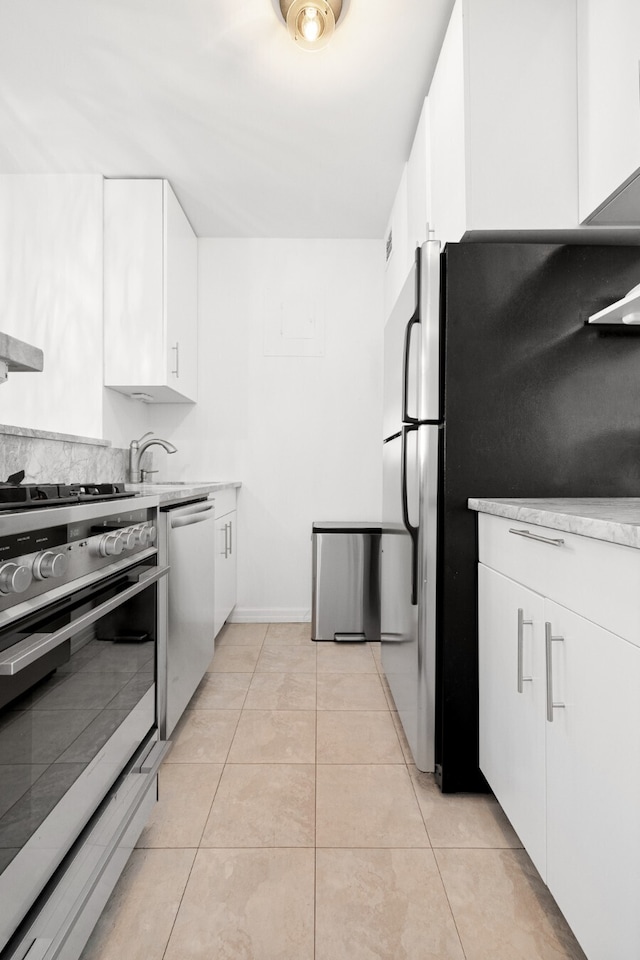 245 E 54th St Unit 30K, New York City, NY 10022 - kitchen featuring appliances with stainless steel finishes, white cabinetry, light countertops, light tile patterned floors, and baseboards