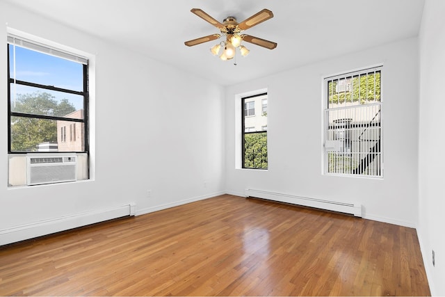 unfurnished room featuring baseboard heating, wood-type flooring, cooling unit, and a healthy amount of sunlight