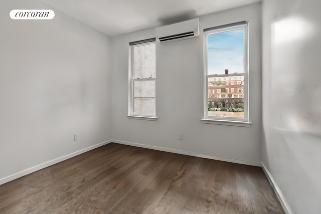 unfurnished room with dark hardwood / wood-style floors and an AC wall unit