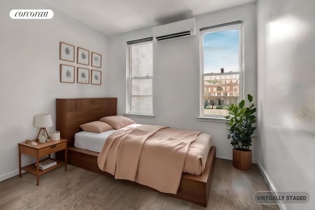 bedroom featuring hardwood / wood-style floors and an AC wall unit