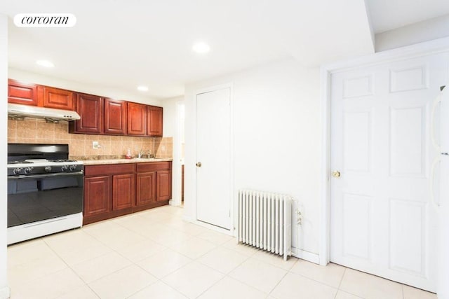 kitchen with radiator, range with gas stovetop, sink, decorative backsplash, and light tile patterned floors