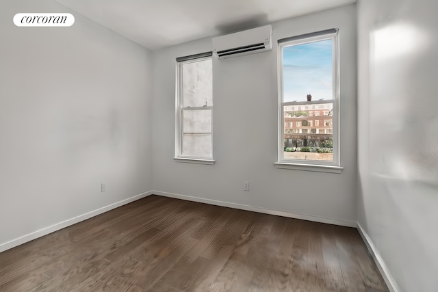 unfurnished room with a wall unit AC, visible vents, baseboards, and wood finished floors