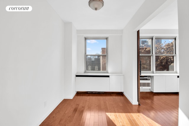 interior space featuring visible vents, baseboards, an AC wall unit, and hardwood / wood-style floors