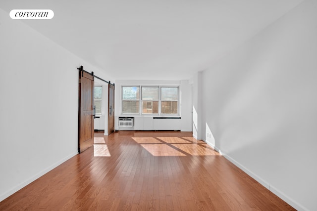 unfurnished living room with light hardwood / wood-style floors and a barn door